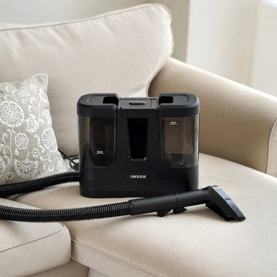Sort Rennoa SpotCleaner med slange og mundstykke på en beige sofa